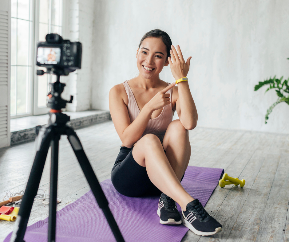 Une femme crée une vidéo de fitness en ligne avec une caméra et un trépied.