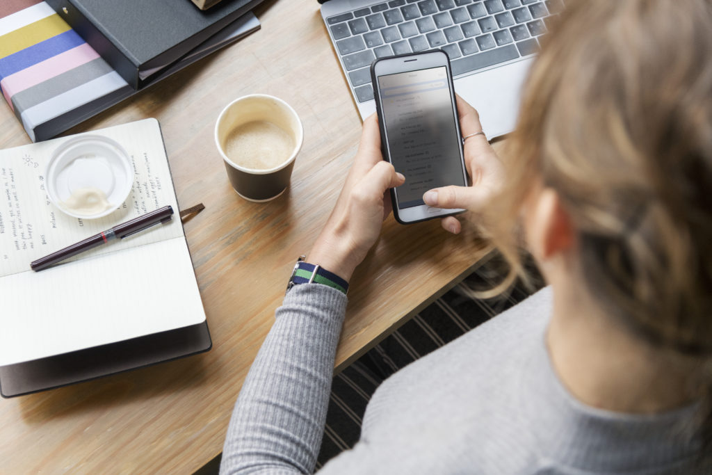 Person at desk using phone with SimplyBook.me client app, highlighting customer long-term loyalty.