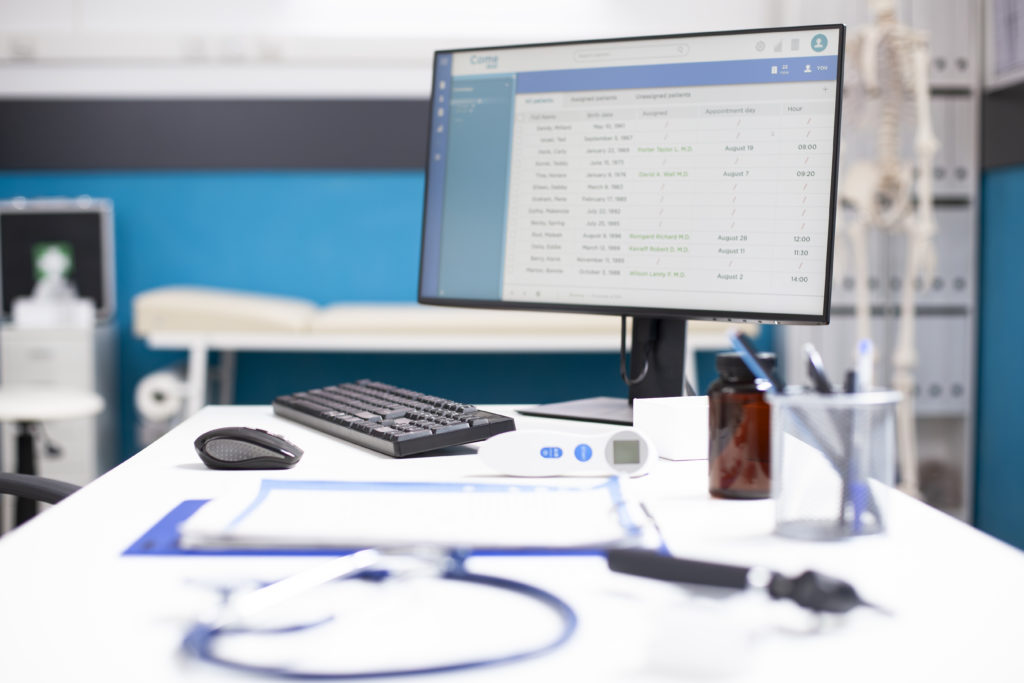 A computer shows a patient schedule, with SimplyBook.me boosting HIPAA-compliant online scheduling and compliance.