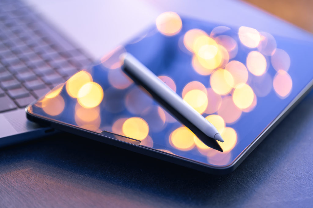 Digital pen on tablet with laptop nearby, highlighting a mobile-first experience using SimplyBook.me for Gen Z clients.