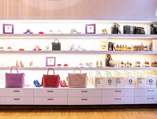 Brightly lit retail display featuring stylish handbags, colorful high heels, and beauty products on elegant white shelves, conveying a chic, modern vibe.