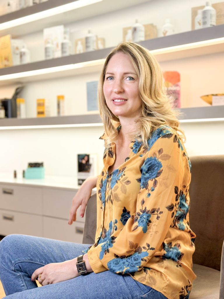 Blonde woman in a makeup studio smiling, highlighting a beauty salon online booking system.