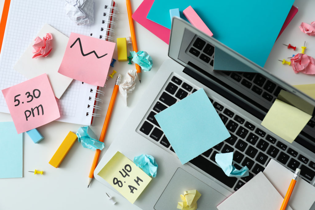Cluttered desk with laptop and notes, highlighting parent-teacher conference scheduling software for organized school meetings.