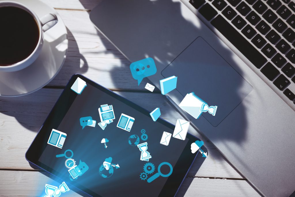 Tablet with glowing blue icons on a desk beside a laptop and coffee, representing digital connectivity for a multi-location business