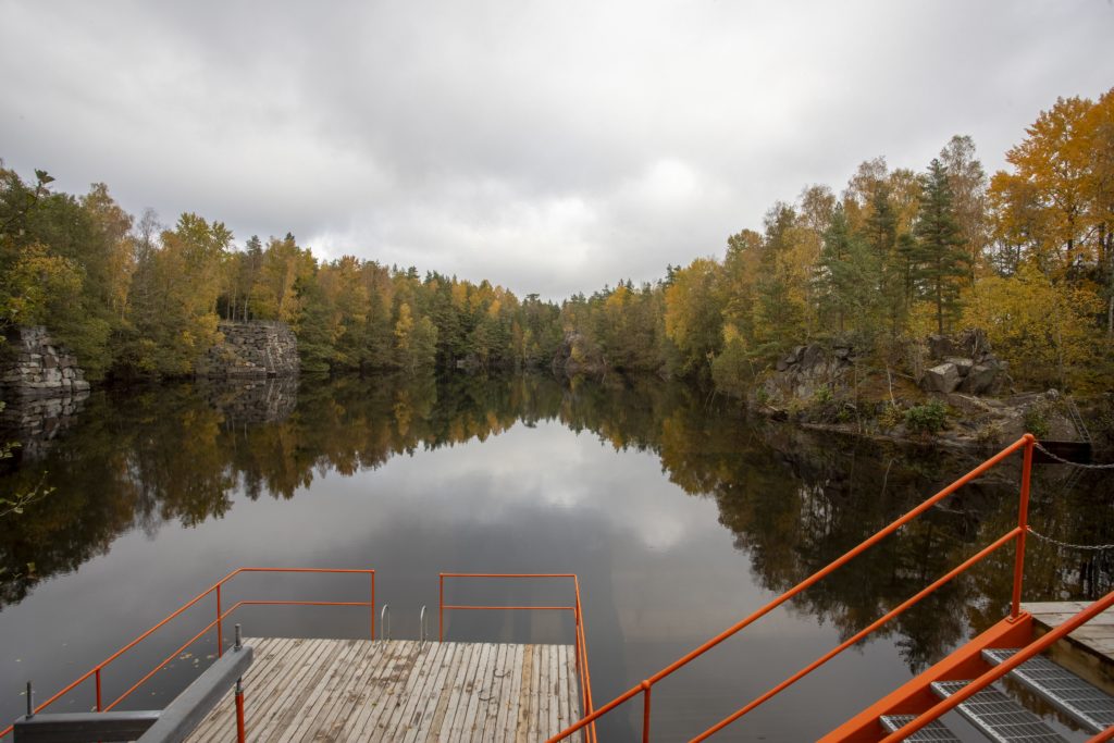 Blick auf den See Gylsboda Kallbadhus, umgeben von herbstlichen Bäumen und felsigen Klippen in Norra Skåne