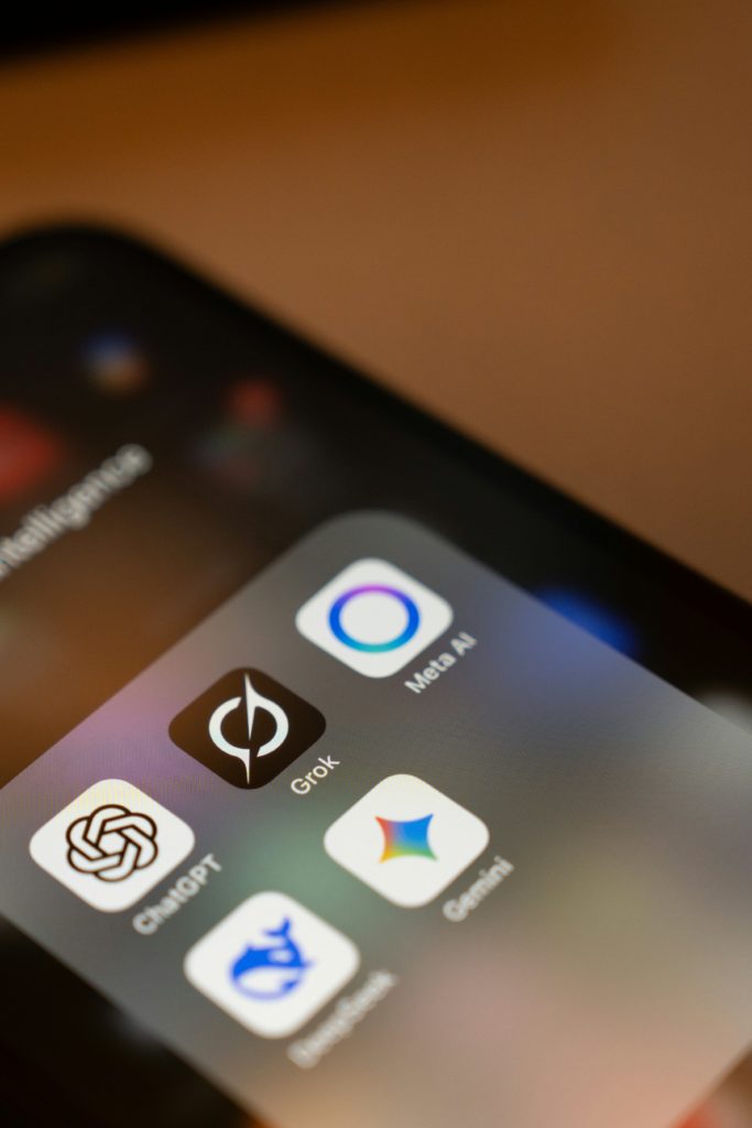 Close-up of a smartphone screen displaying five app icons: ChatGPT, Grok, Meta AI, Deepmind, and Gemini. 